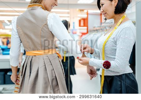 Tailor fitting a bespoke dress to a woman customer with measure tape around her neck