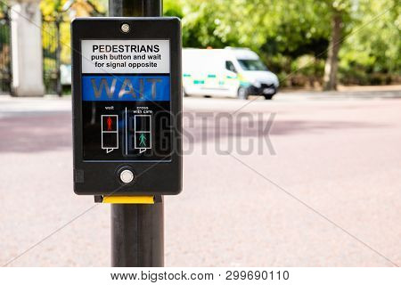 Traffic Light For Pedastrians In Uk For Safe Road Crossing, Blured Police Car In The Background
