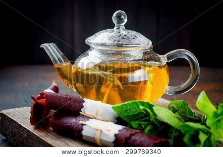 Hot Herbal Tea In A Tea Pot, Leaves Fresh Mint, Dry Fruits Leather Roll And Dry Mint Leaves With Str