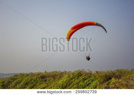 Querim, Goaindia - 19.01.2019 A Tandem Of Paragliders On A Yellow Red Black Parachute Flying Over Gr