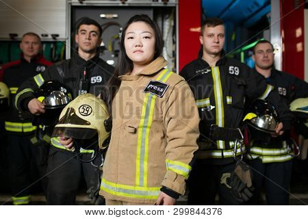 Portrait of four young male and female firefighters on background of fire truck