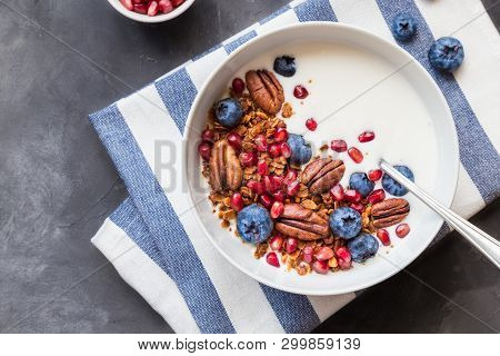 Homemade Granola, Muesli With Pomegranate Seeds, Blueberries, Pecan Nuts And Yogurt On Gray Concrete