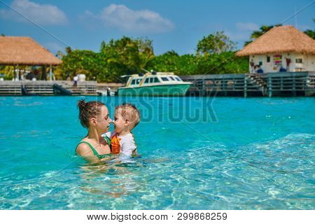 Three year old toddler boy on beach eskimo kissing his mother. Summer family vacation at Maldives.
