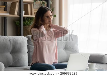 Woman Sitting On Couch Near Computer Suffers From Neck Pain