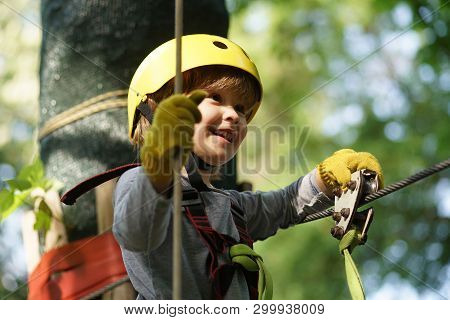 Climber Child On Training. Cute Little Boy In Climbing Safety Equipment In A Tree House Or In A Rope