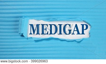 Medigap. Text On White Paper On Torn Blue Paper Background