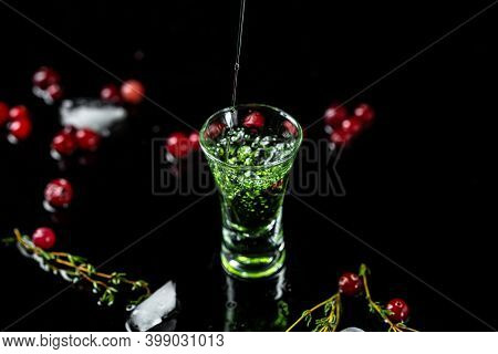 Shot Absinthe Poured Into A Glass. Bottle Of Absinthe With Cranberries And Lime Isolated On Black Ba