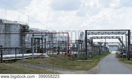 Refinery Factory Oil Storage Tank And Pipeline Steel At Day On Framatic Sky Background. Oil Refinery