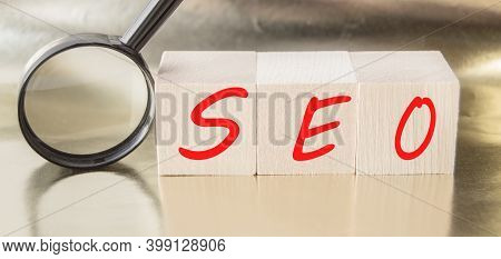 Seo Search Engine Optimization Text Wooden Cubes And Magnifying Glass On A Golden Background. Idea, 