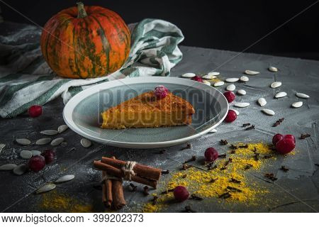 A Delicious Piece Of Pumpkin Pie On A Stone Table, Surrounded By Cinnamon Sticks, Cranberries. In Th