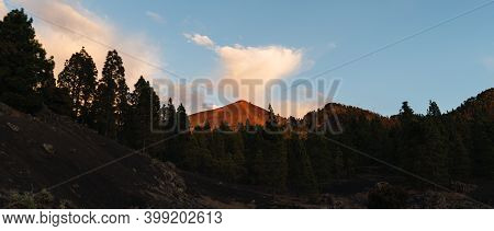 Peak Of A Volcano Among Sunlit Clouds