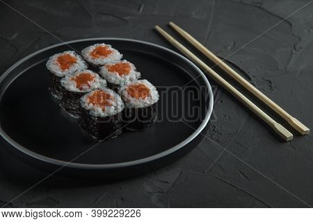 Classic Sushi With Salmon On A Beautiful Plate, On A Stone Black Table. Nearby Are Chinese Sticks. T