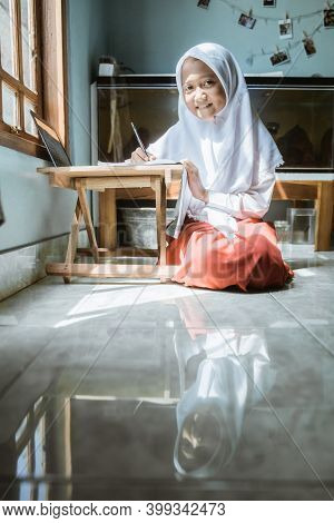 Indonesian Schoolgirl Studying Homework During Her Online Lesson