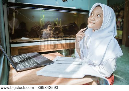 Indonesian Schoolgirl Studying Homework During Her Online Lesson