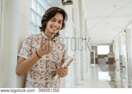 Portrait Of Happy Male Student Holding Book