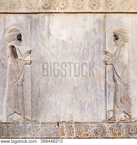 Ancient wall with bas-relief - two assyrian warriors with spears, Persepolis, Iran. Square background with embossed image persian bearded mans. Mock up template. Copy space for text