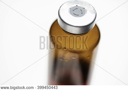 A Macro Shot With Selective Focus Of An Amber Color Vaccine Injection Bottle Set On Plain White Back