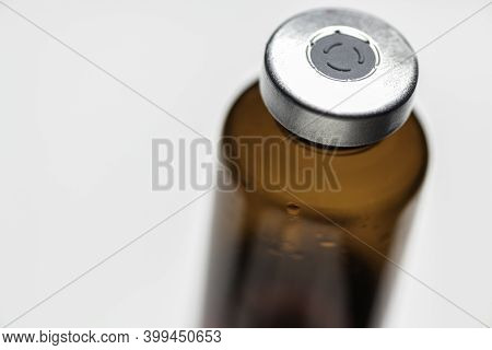 A Macro Shot With Selective Focus Of An Amber Color Vaccine Injection Bottle Set On Plain White Back