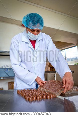 Guaranda, Bolivar / Ecuador - November, 2013: A Worker At A Local Chocolate Factory, In A White Coat