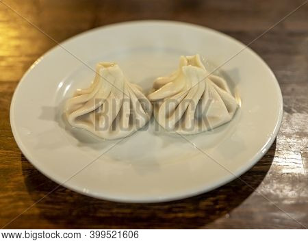 Two Hinkali Dish. Georgian Cuisine On Plate On Wooden Table.
