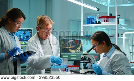 Team Of Microbiology Scientists Discussing About Virus Development Working Overtime In Modern Equppe