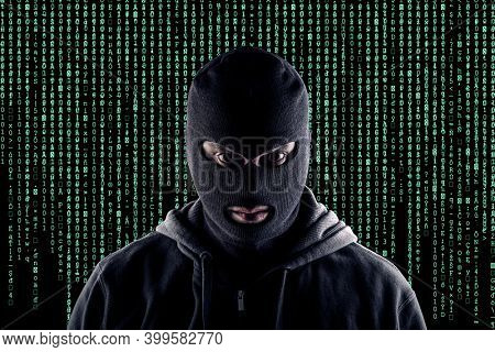 Masked cyber terrorist with black balaclava and hoodie in the dark
