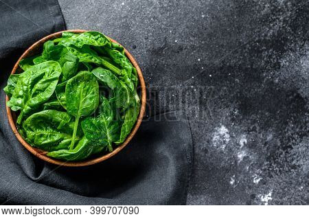 Fresh Spinach Leaves In A Wooden Bowl. Black Background. Top View. Copy Space
