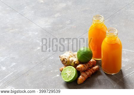 Healthy Drink From Turmeric And Ginger Roots And Lime In Small Bottles On Grey Concrete Background W