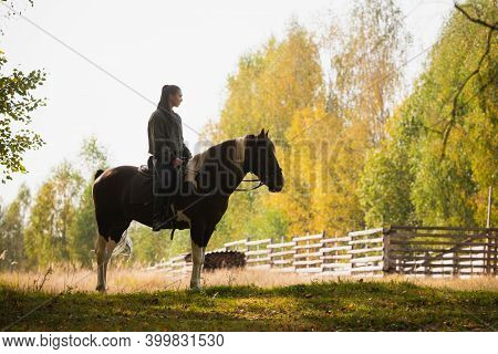 Silhouette Of A Rider On A Horse Against The Background Of An Autumn Forest.