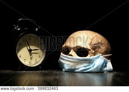Covid Concept. Human Skull In Medical Mask Near Alarm Clock