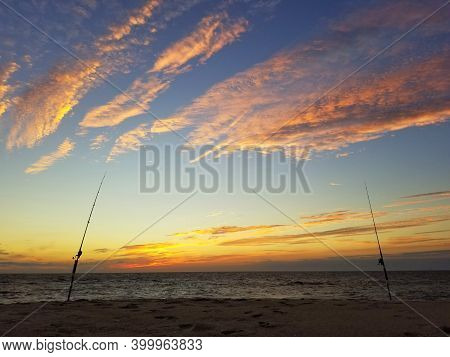 The Silhouette Of Two Surf Fishing Rods On The Beach During Early Morning Near Dewey Beach, Delaware