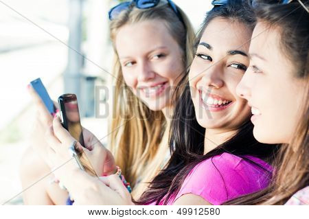 Three Girls Chatting With Their Smartphones