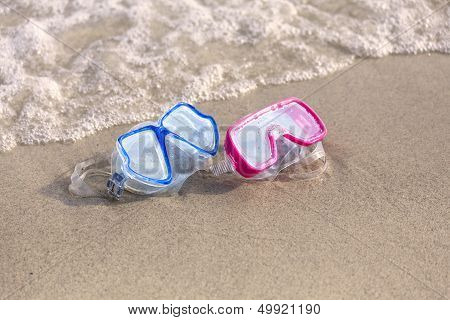 Summer Time: Red And Blue Gogles On The Sand Washed By The Ocean