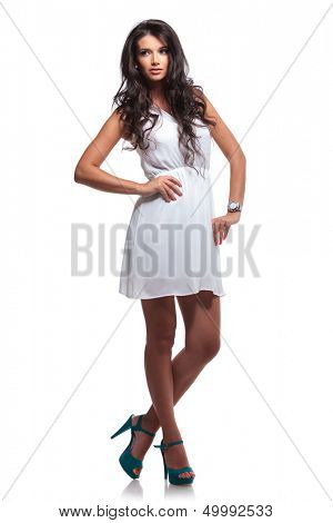 full length picture of a young beautiful woman looking away while holding her hands on her hips. isolated on a white background