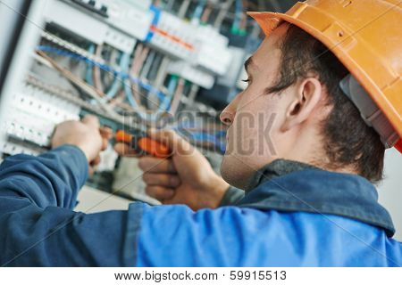 Young adult electrician builder engineer screwing equipment in fuse box