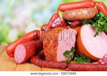 Lot of different sausages on wooden table on natural background