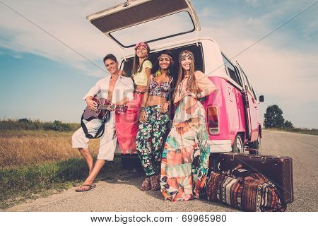 Multi-ethnic hippie friends with guitar on a road trip