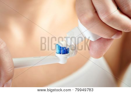 Hands Squeezing Toothpaste On Electric Toothbrush Macro