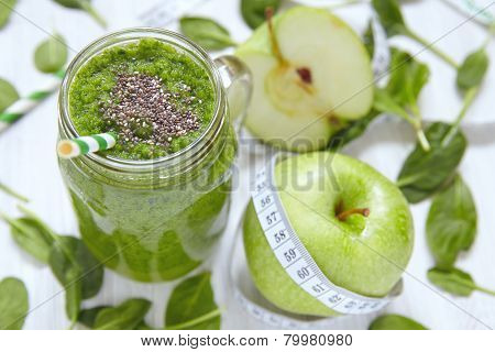 Apple and spinach smoothie in glass on a wooden background