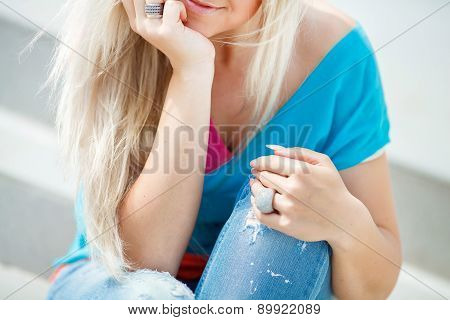 Stylish beautiful girl sitting on the stairs in bright clothes