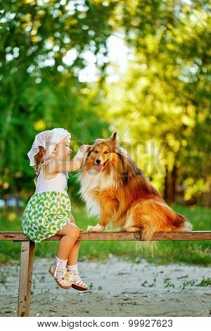 Little Girl And Dog Sitting On A Bench.