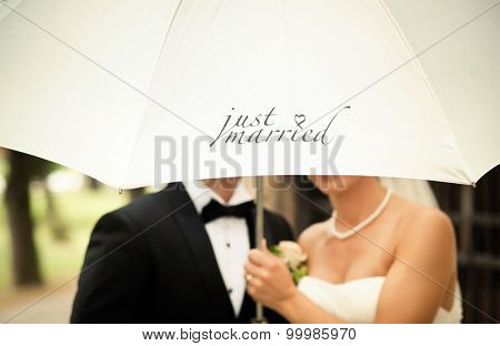 Just married couple holding white umbrella with text