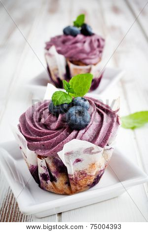 blueberry cupcakes with frosting, blueberries and mint leaves