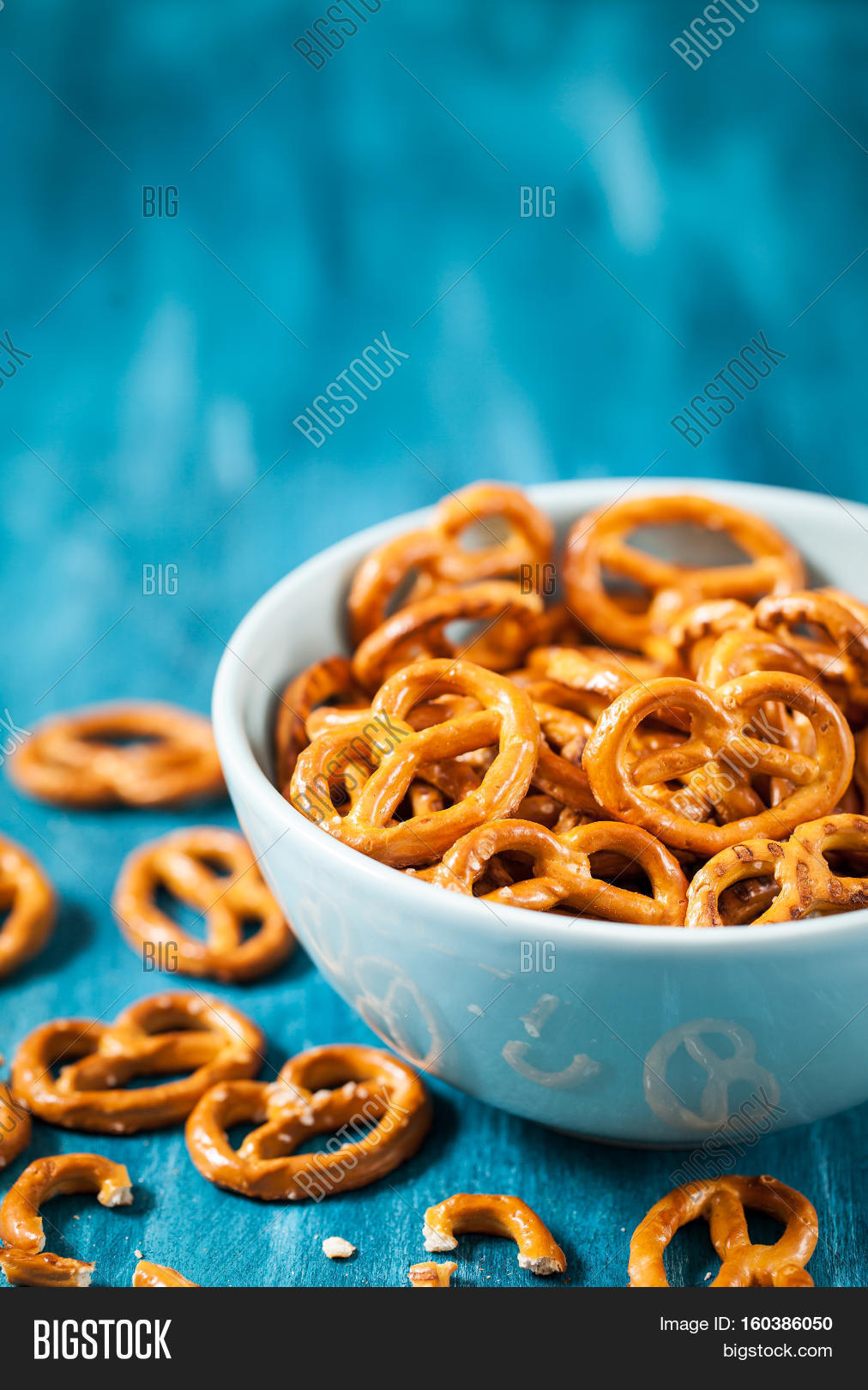 salty snacks mini pretzels in bowl on blue wooden table