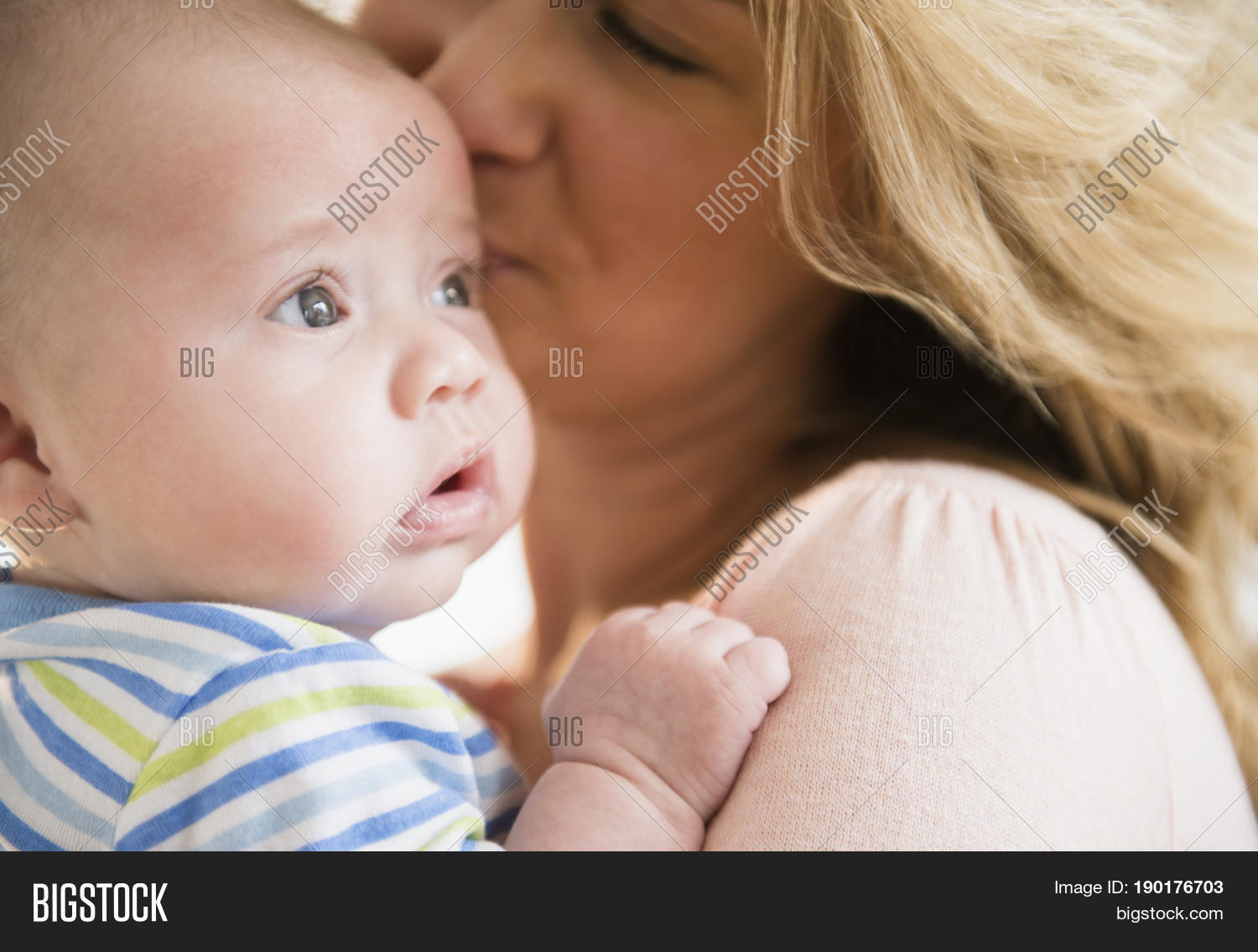 caucasian mother kissing baby