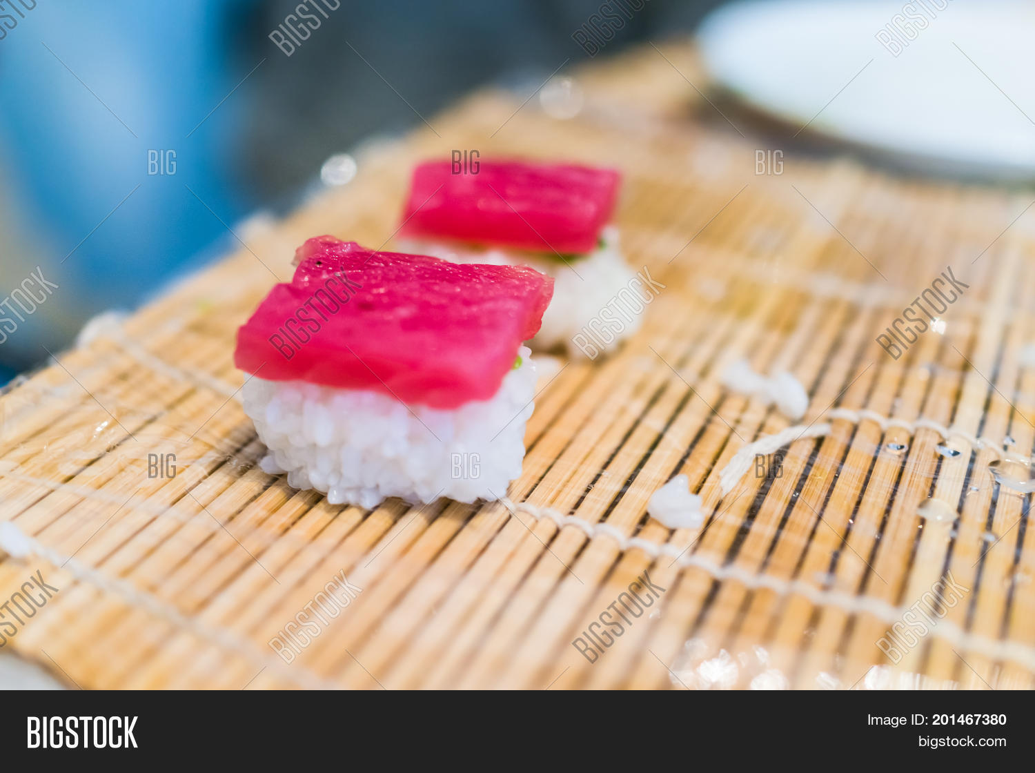 macro closeup of nigiri tuna sushi on mat with plastic wrap