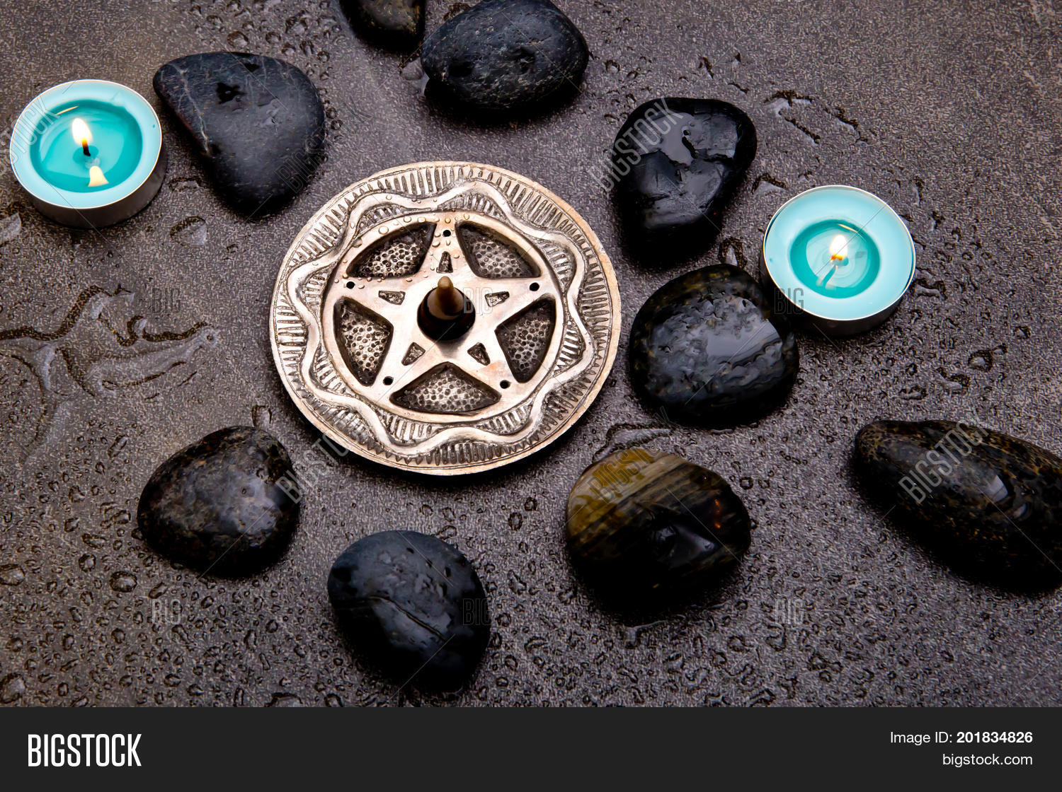 incense burning in silver pentagram with blue candles and black