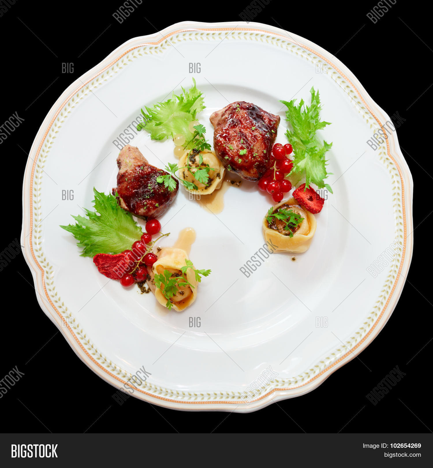 duck meat with berries and ravioli in plate, isolated on black