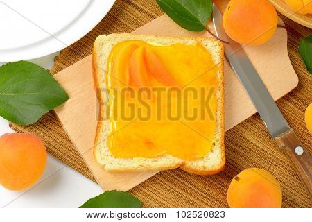 overhead view of white toast greased with apricot marmalade