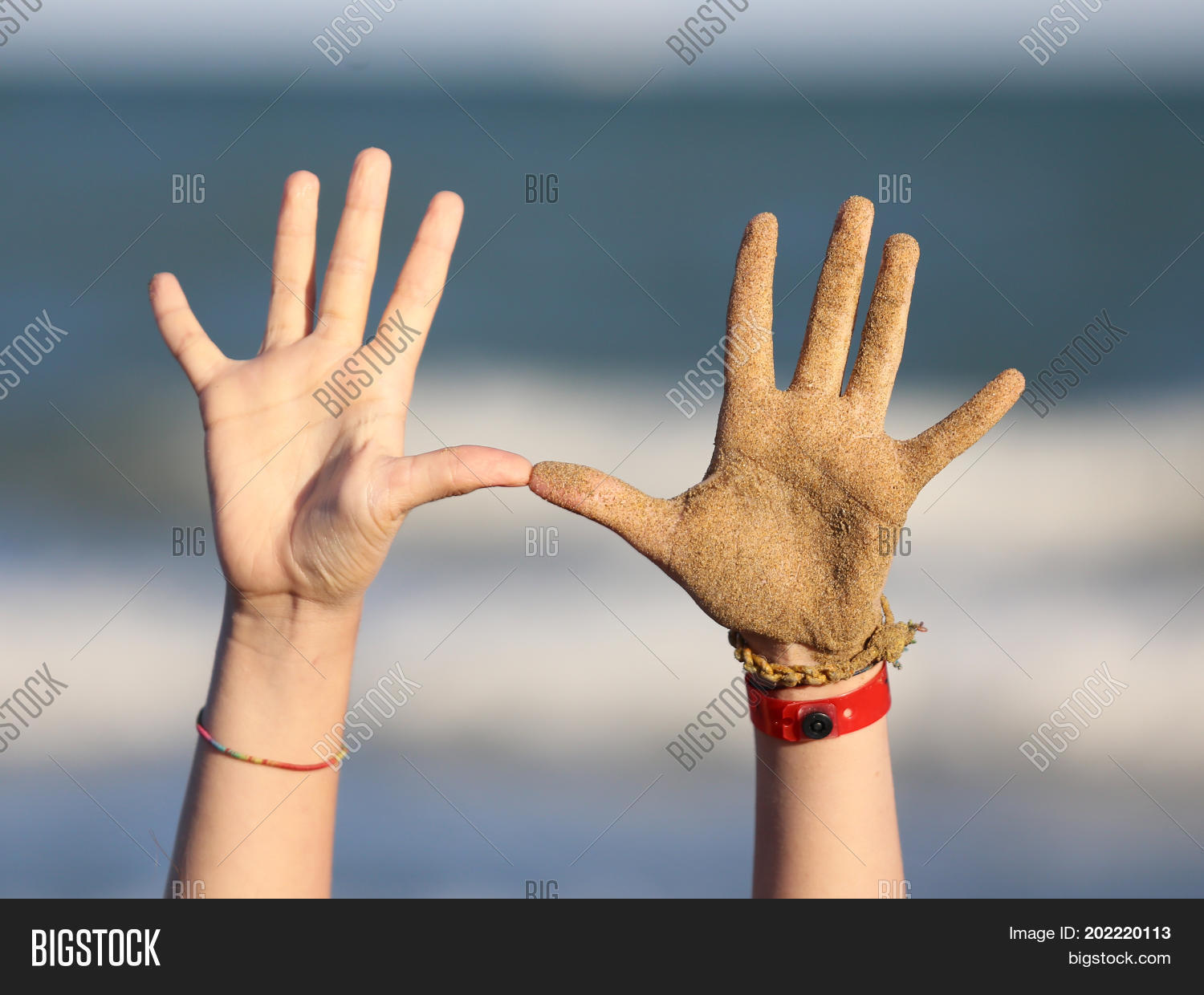 ten fingers and two hands of a child on the beach near the sea